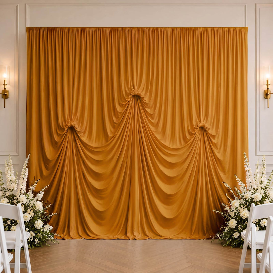 Golden draped wedding backdrop with white floral aisle decor