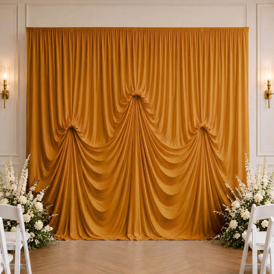 Golden draped wedding backdrop with white floral aisle decor