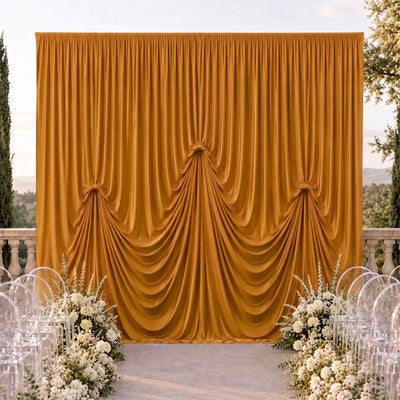 Elegant outdoor wedding backdrop with gold draped curtains and white floral arrangements