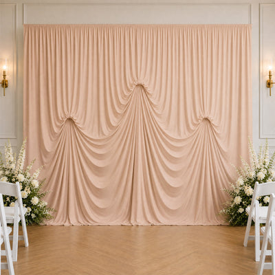 Elegant blush draped wedding backdrop with white floral arrangements and chairs