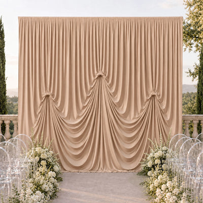 Elegant champagne draped wedding backdrop with floral aisle and clear chairs