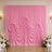 Pink draped wedding backdrop with floral arrangements and white chairs