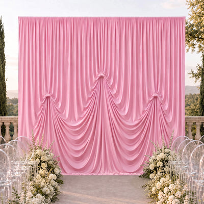 Pink draped wedding backdrop with white floral aisle decor outdoors