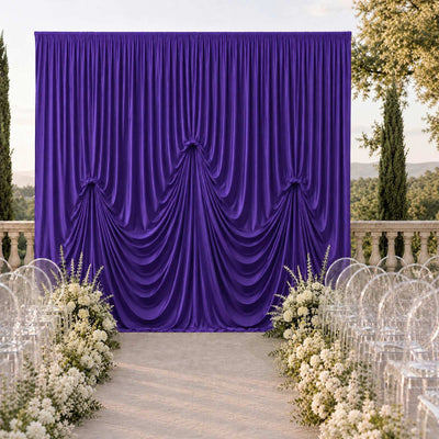 Purple draped wedding backdrop with floral aisle and clear chairs outdoors