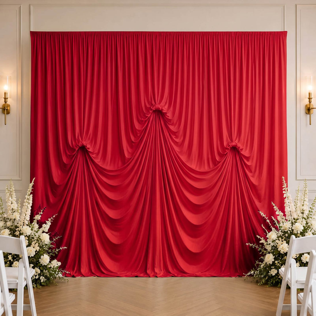 Red draped wedding backdrop with white floral arrangements in elegant venue