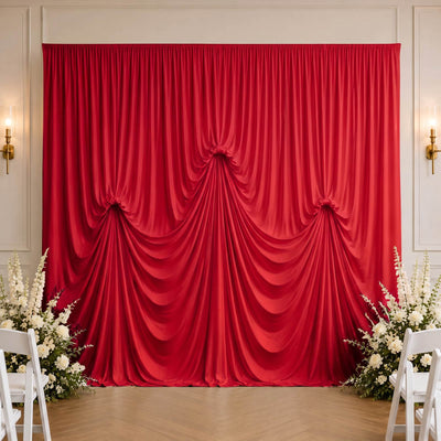 Red draped wedding backdrop with white floral arrangements in elegant venue