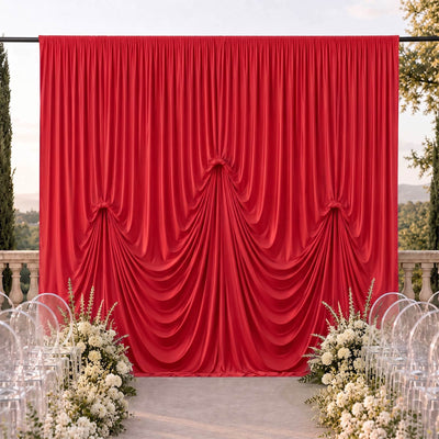 Red draped wedding backdrop with white floral aisle decor outdoors