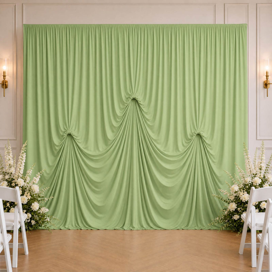Mint green draped wedding backdrop with white floral arrangements and chairs
