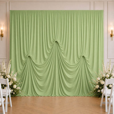 Mint green draped wedding backdrop with white floral arrangements and chairs