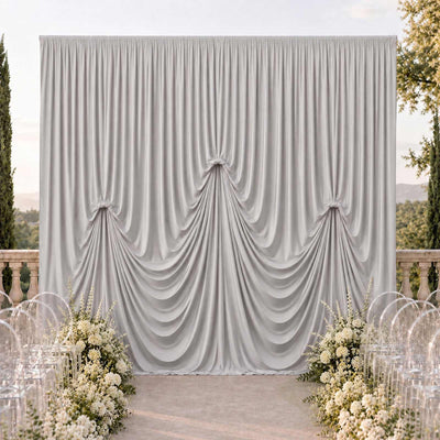 Elegant draped wedding backdrop with floral aisle and clear chairs outdoors