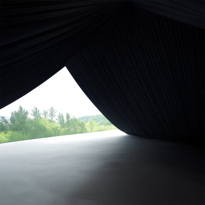 Black draped fabric with a view of greenery outside