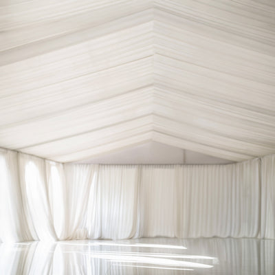 Elegant white draped fabric backdrop in a spacious studio setting.