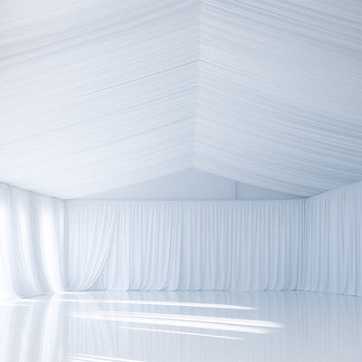 Empty white room with draped fabric and reflective floors.
