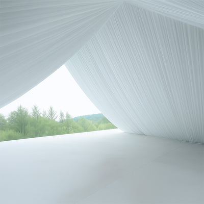 White draped fabric with greenery view through an open space.