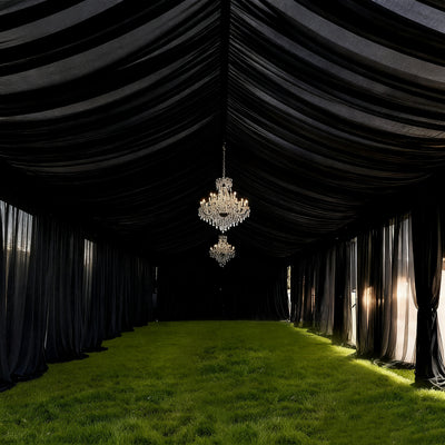 Elegant black tent interior with chandeliers and lush green grass flooring.