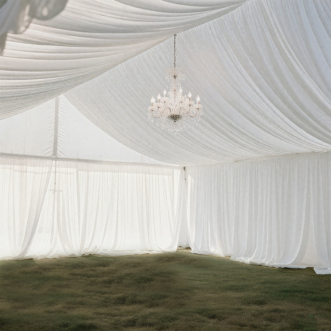 Elegant white draped tent interior with a sparkling chandelier.