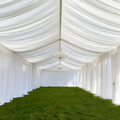 Elegant white marquee with chandeliers and grass flooring.