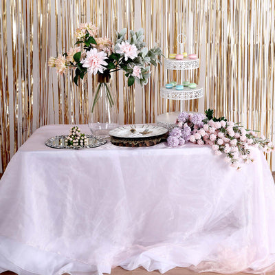 Elegant table setup with flowers, cake stand, and decorative plates.