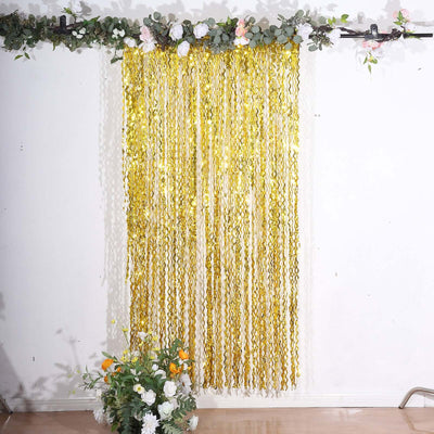 Gold fringe curtain backdrop with floral accents for party decoration.
