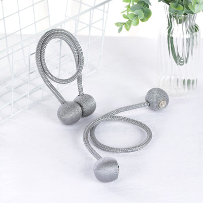 Gray decorative rope with weighted ends on a white surface.