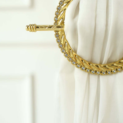 Gold curtain tieback with decorative beads on a white fabric.