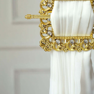 Elegant gold curtain tieback with decorative detailing and white fabric.