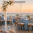 Elegant beach wedding reception with blue linens, pearls, and floral arch at sunset