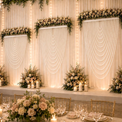 Elegant wedding stage with white floral decor, draped backdrop, and candlelight
