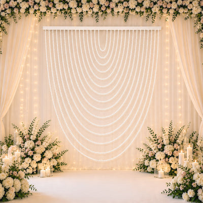 Elegant floral wedding backdrop with white drapes, candles, and pearl garlands