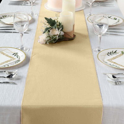 Elegant gold table runner on a dining table set with floral plates and candles.