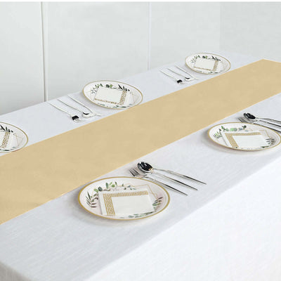 Elegant gold table runner on a white table setting with decorative plates and cutlery.