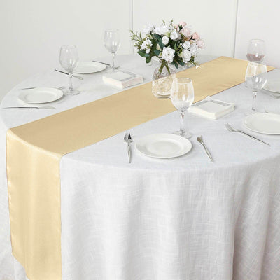 Gold satin table runner on a round table set for dining.