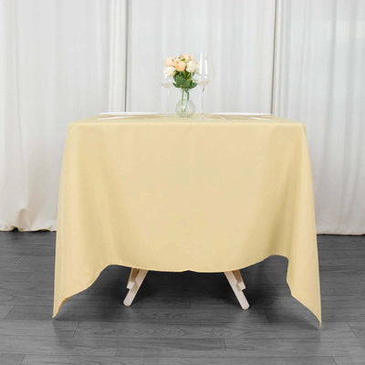 Yellow tablecloth draping a round table set for dinner with flowers and glasses.