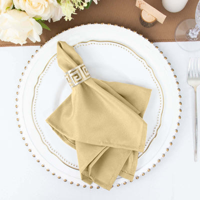 Elegant gold napkin with decorative ring on a white plate.