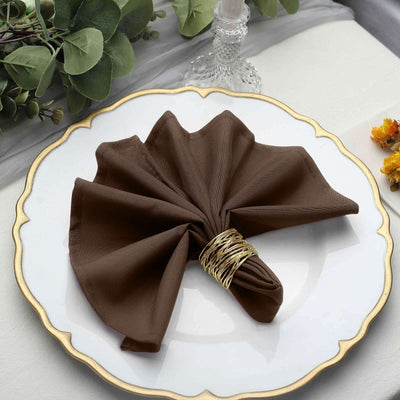 Brown napkin elegantly folded on a decorative plate with a golden rim.