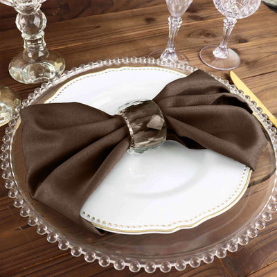 Elegant brown napkin with crystal ring on a vintage plate setting.