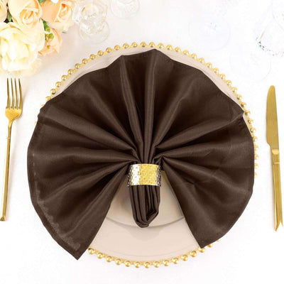 Elegant brown napkin elegantly folded on a gold-rimmed plate.