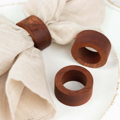 Set of wooden napkin rings on a linen napkin.