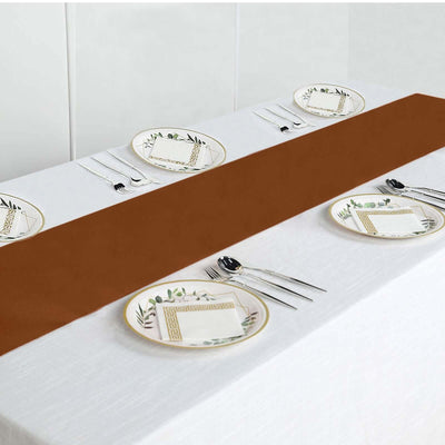 Brown table runner on a white table setting with decorative plates and utensils.