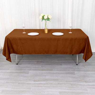 Brown tablecloth draped on a table with plates and glasses.