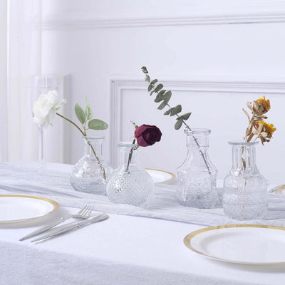 Clear glass vases with flowers on a white table setting