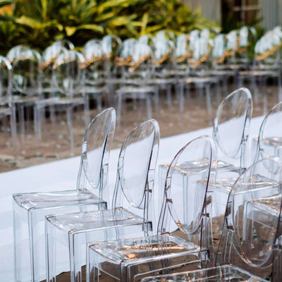Transparent ghost chairs arranged for an event in a stylish outdoor setting.