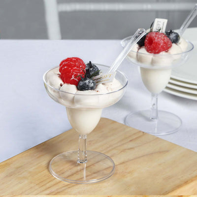 Delicious dessert with berries and cream in a clear cup on a wooden board.