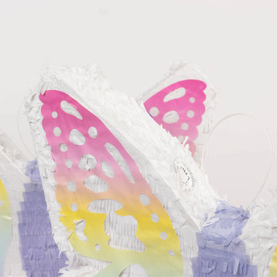 Colorful butterfly piñata with fringed details on a white background.