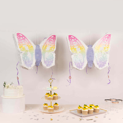 Colorful butterfly piñatas hanging above a dessert display.