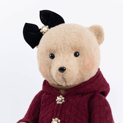 Vintage teddy bear in burgundy sweater with black bow on white background