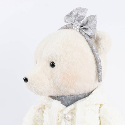 White plush teddy bear with silver bow and pearl headband on white background