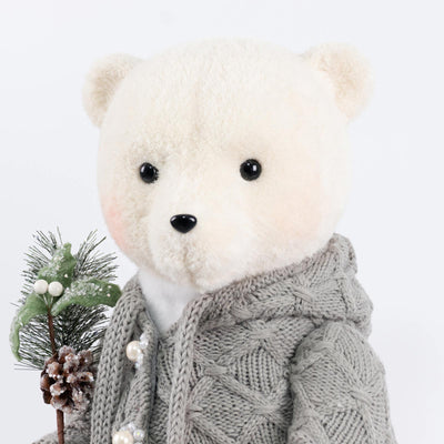 White teddy bear in gray knit sweater holding a pinecone holiday decoration