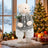 White teddy bear in Christmas sweater beside decorated tree and gifts
