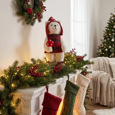 Christmas mantel decor with teddy bear, garland, stockings, and lights